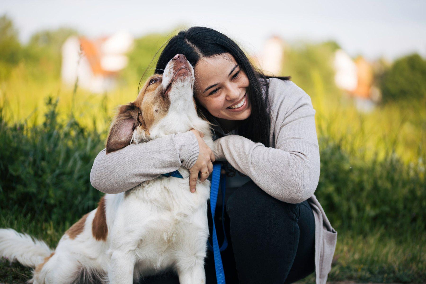 Une femme serre son chien dans ses bras dans un pré